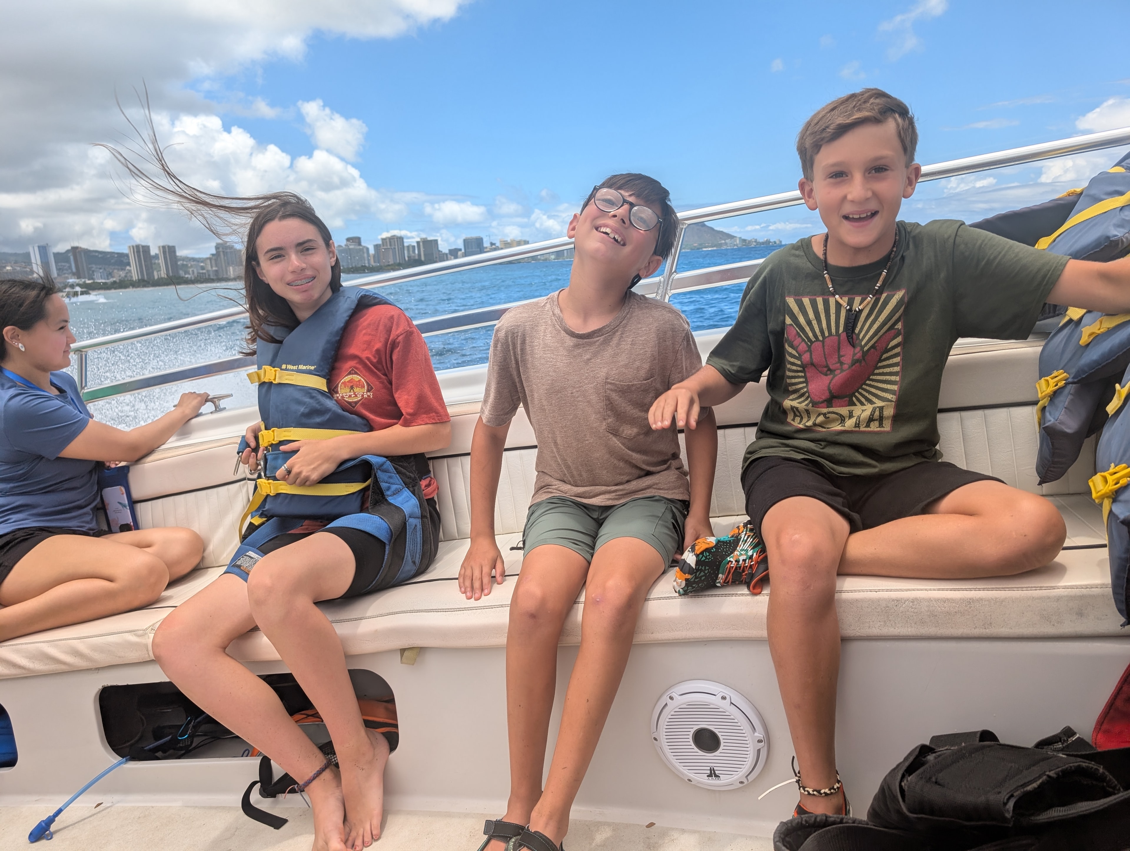 Kids laughing on a boat with Honolulu skyline in the background