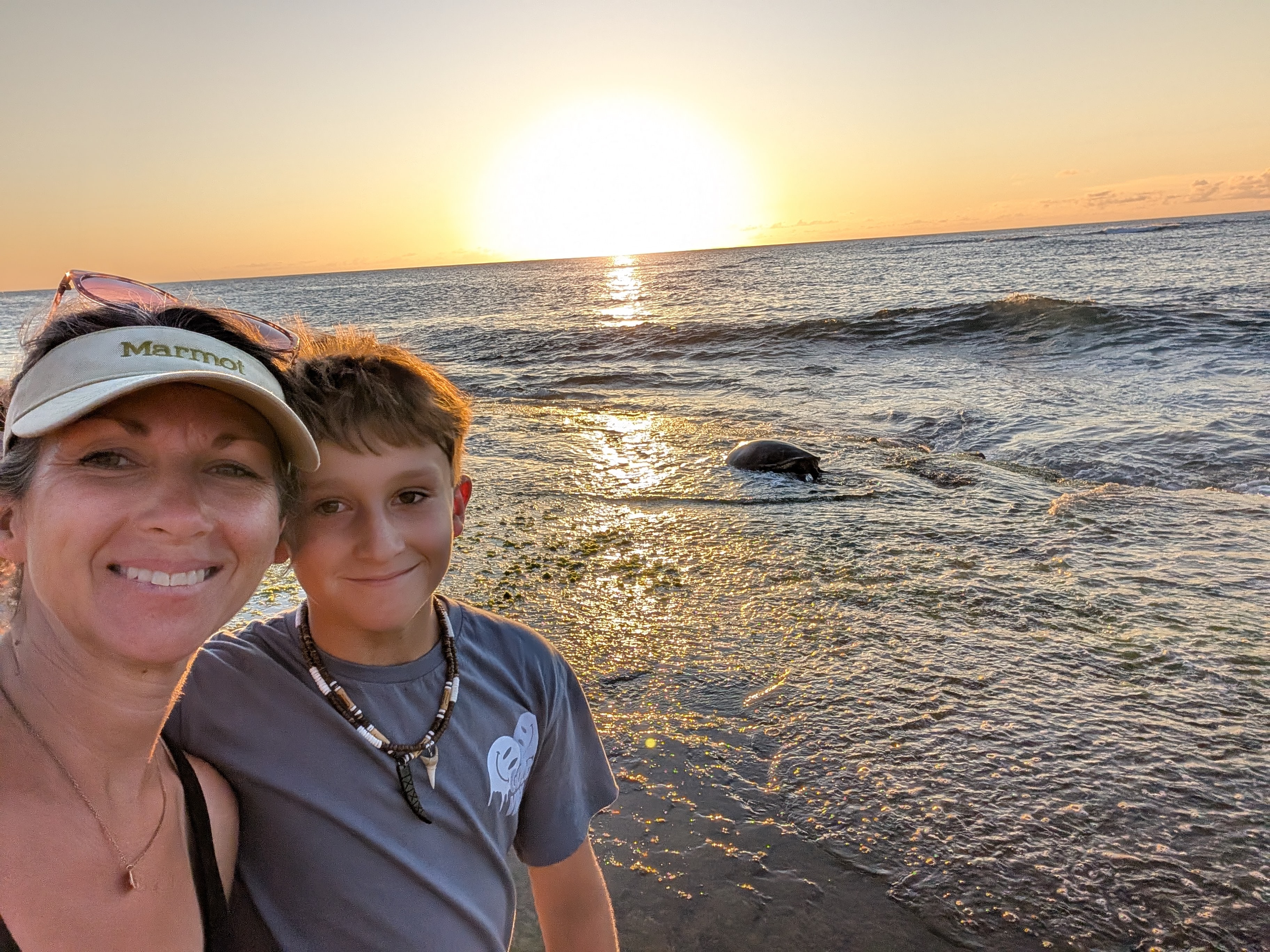 Mom and son selfie with sea turtle at sunset in Oahu